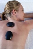 Warmsteinmassage - Frau liegt auf der Massagebank