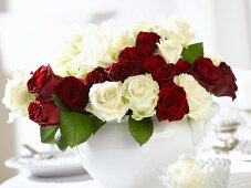 Arrangement of red and white roses on laid table
