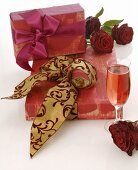 Geschenke, rote Rosen und Sektglas