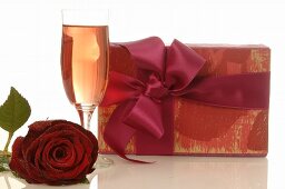 Gift, red rose and glass of sparkling wine