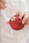 Child threading string through top of Christmas bauble