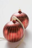 Two red Christmas baubles with gold stripes and spots