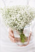 Woman holding a bouquet of gypsophila in a vase