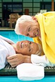 Älteres Paar in Bademänteln am Swimmingpool