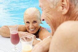 Germany, senior couple drinking cocktail at pool