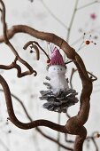 A homemade gnome hanging on a tree branch