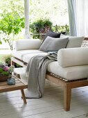 A wooden sofa with upholstered cushions on a summery veranda