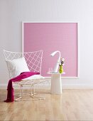 Wire chair and side table in front of pink wallpaper in picture frame