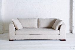 Weisses Sofa vor weiss gestrichener Ziegelwand