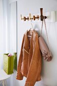 Leather jacket & handbag hanging on DIY coat rack with doorknobs as hooks