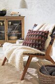 A blanket and a knitted Jacquard-style cushion on a chair
