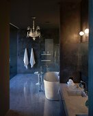 Intricate, gold pendant lamp in luxurious, dark designer bathroom with reflective floor and marble washstand