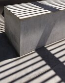 Patterns of light and shade on concrete block under wooden pergola