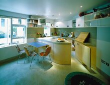 Open kitchen with modern built-in, curved counter and dining area with chairs