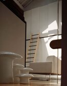 Multi-piece side table set and ladder resting on a white, designer built in cupboard