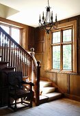 Wooden stairs and banister in a traditional home with wood paneling on the wall