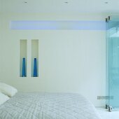 Weisses Schlafzimmer mit Doppelbett und indirektem blauen Licht in horizontaler Wandnische