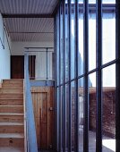 Treppenraum mit rustikaler Holztreppe vor Glasstahlfassade