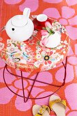 A teapot and a teacup on a Moroso table with a floral pattern