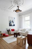 weiße Sofagarnitur und Beistelltische in einem Wohnzimmer mit Stuckdecke
