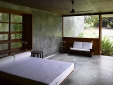 Puristischer Schlafraum aus Beton mit Doppelbett und weisser Bettwäsche