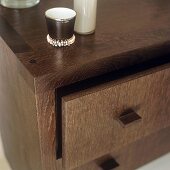 A decorative porcelain cup on a chest of drawers made of dark wood