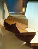 A modern spiral staircase with wooden steps and a glass balustrade