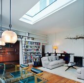 Living-dining room with skylight and light grey sofa set in front of fireplace