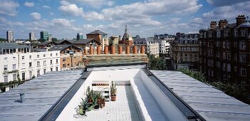 Elongate roof terrace between metal roofs with view of an English cityscape