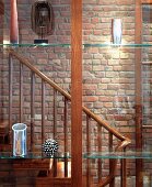 Blick durch Fensterscheiben mit dekorierten Glasborden in Treppenraum mit schlichtem Holzgeländer vor Backsteinwand