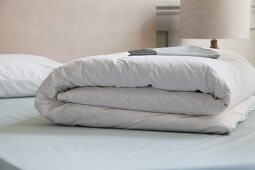 Zusammengelegte weiße Bettdecke auf Bett
