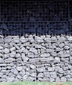 Gabion fence of stacked stone in wire cages