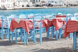 Tische einer griechischen Taverne am Hafen; rot-weiss karierte Tischdecken sorgen für eine heitere Stimmung
