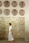Frau durchschreitet meditativen Raum - aufgehängter Wandschmuck an Sturz über Durchgang und Blick auf Natursteinwand