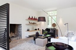 Designer living room with arc lamp above dark brown coffee table in front of open fireplace