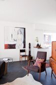 Offener Wohnraum eines Appartements mit moderner Kunst und 50er Jahre Vintagemöbeln auf dunklem Schieferboden