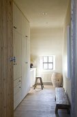Open interior door with view into simple, narrow room with fitted wardrobes and workspace