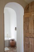 Open, arched interior door with view into renovated bathroom