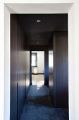 Minimalist hallway with dark wood fitted cupboards