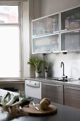 Moderne Küchenzeile mit Edelstahlfronten und Hängeschränke mit Mattglastüren