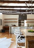 Modern mixture of styles in open kitchen-dining room with designer barstools at counter and white, 50s classic chairs with animal-skin covers at rustic table
