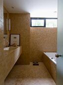 Modern bathroom with sand-coloured tiles on floor, walls, washstand and bathtub