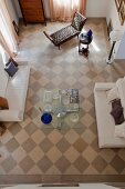 Vogelperspektive auf das Schachbrettmuster eines Holzbodens in Wohnzimmer mit moderner Sitzgarnitur und einzelnen Antiquitäten