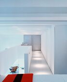 weiße Galerie mit Einbauschränken und Blick auf Sessel im Wohnraum