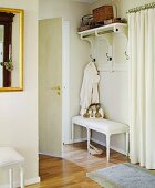 Hallway with coat rack on wall and antique, white bench
