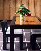 Black-framed table with light wood top, matching chairs and vase of flowers