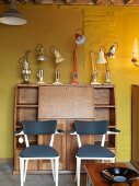 Bureau with desk lamps in front of yellow wall
