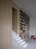 Modern seminar room - stairs formed from single, solid block in front of long, metal bookshelves on wood-clad wall