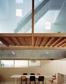 Dining table and chairs under suspended wooden ceiling & stairs