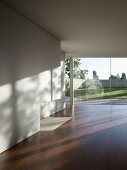 Leerer Wohnraum mit Holzboden & Terrassenfenstern